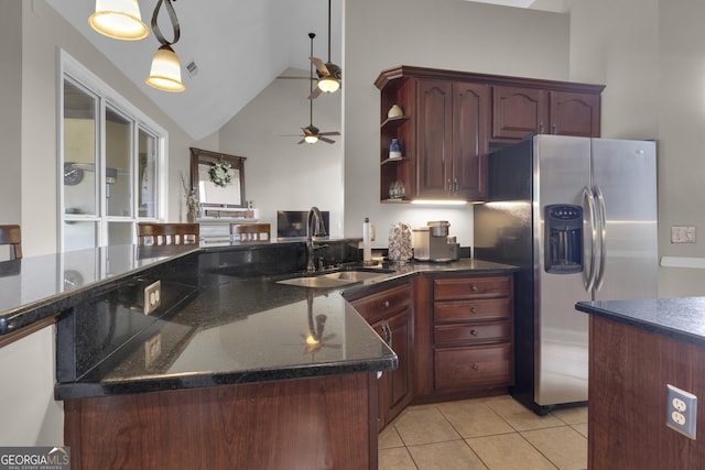 kitchen with sink, hanging light fixtures, dark stone countertops, light tile patterned floors, and stainless steel fridge