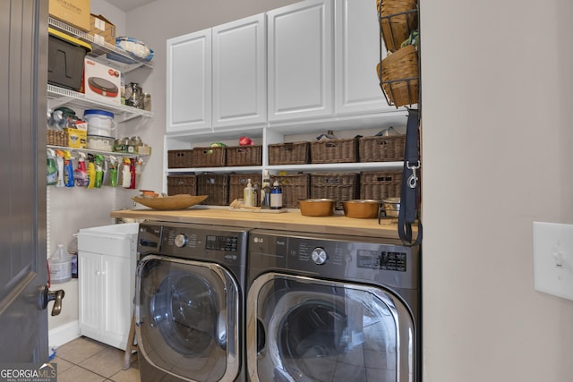 laundry area featuring cabinets, light tile patterned floors, and washer and clothes dryer