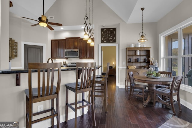 kitchen featuring dark brown cabinets, dark hardwood / wood-style floors, pendant lighting, and a kitchen bar