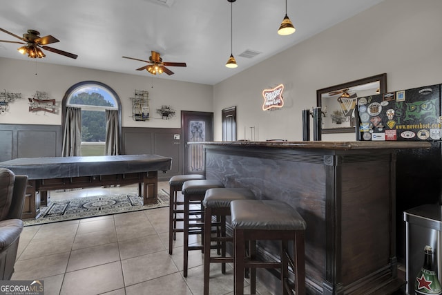 bar with light tile patterned floors and decorative light fixtures