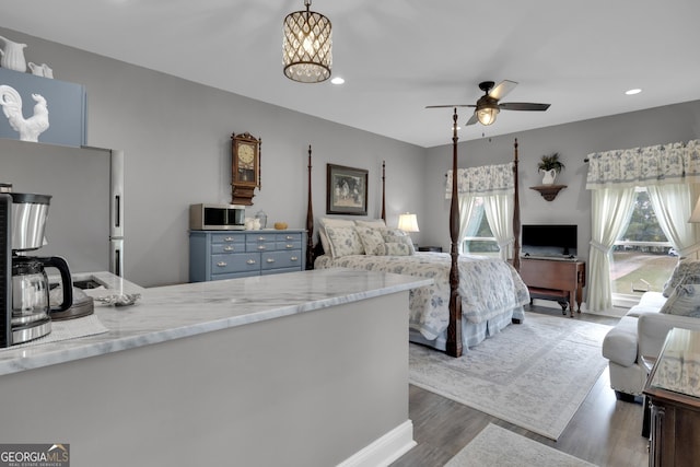 bedroom featuring stainless steel refrigerator, dark hardwood / wood-style flooring, and a notable chandelier