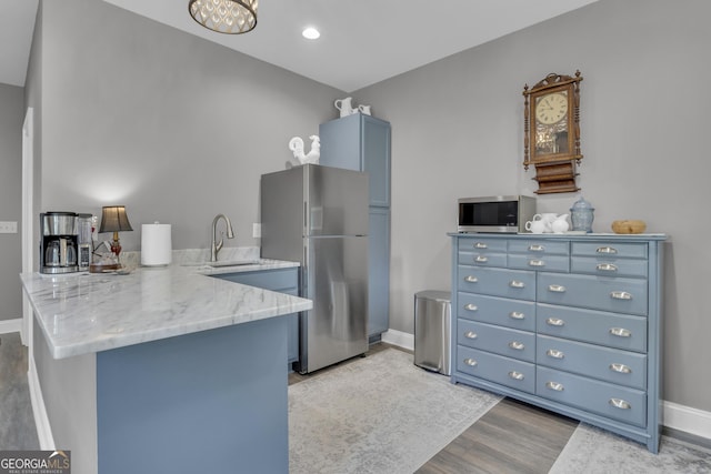 kitchen featuring blue cabinets, sink, appliances with stainless steel finishes, kitchen peninsula, and light hardwood / wood-style floors