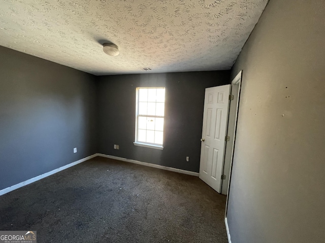 empty room featuring dark colored carpet and a textured ceiling