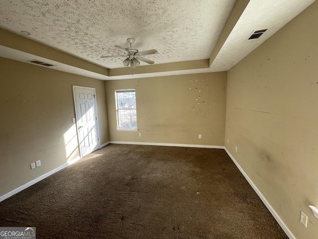 empty room featuring a raised ceiling, a textured ceiling, and carpet flooring