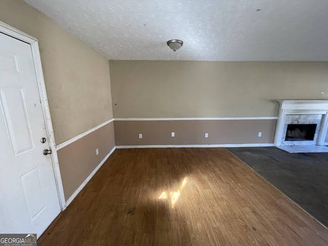 unfurnished living room with dark wood-type flooring, a fireplace, and a textured ceiling