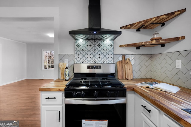 kitchen with exhaust hood, white cabinetry, wooden counters, gas range oven, and backsplash