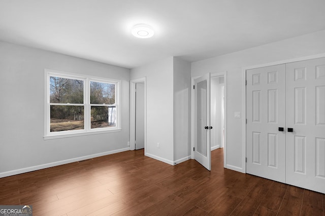 unfurnished bedroom with dark hardwood / wood-style floors and a closet