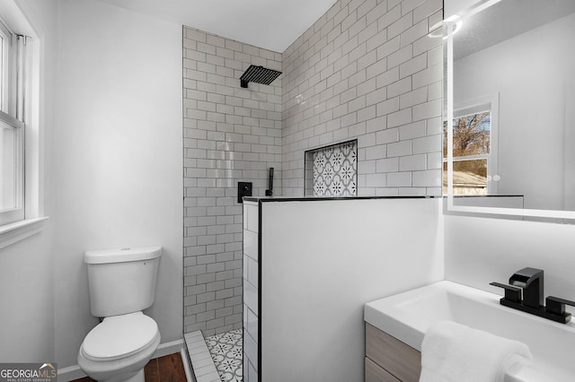 bathroom with vanity, toilet, and a tile shower