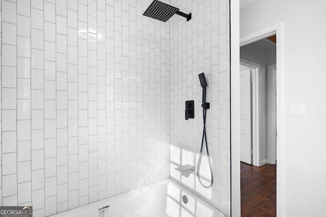 bathroom with hardwood / wood-style floors and tiled shower / bath