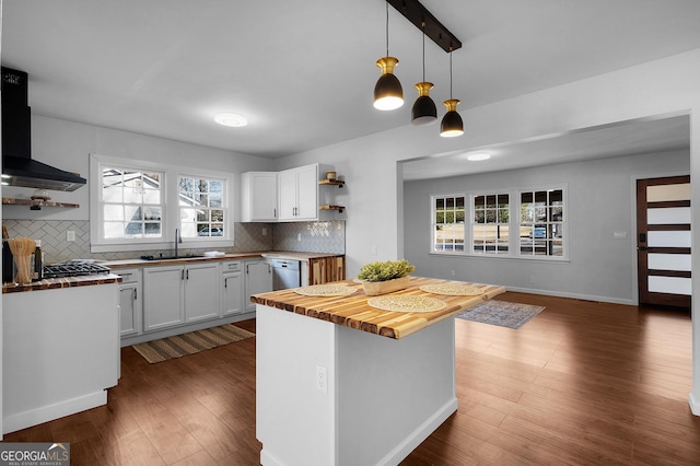 kitchen featuring range hood, dishwasher, butcher block counters, white cabinets, and hanging light fixtures