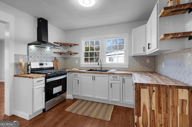 kitchen with white cabinetry, sink, wooden counters, stainless steel gas range oven, and wall chimney exhaust hood