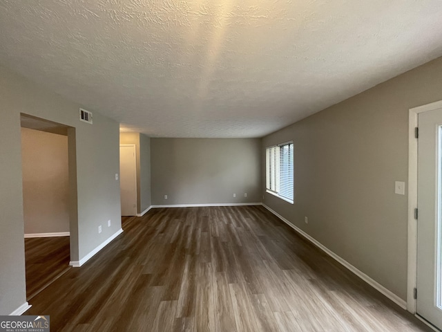 empty room with dark wood-type flooring and a textured ceiling