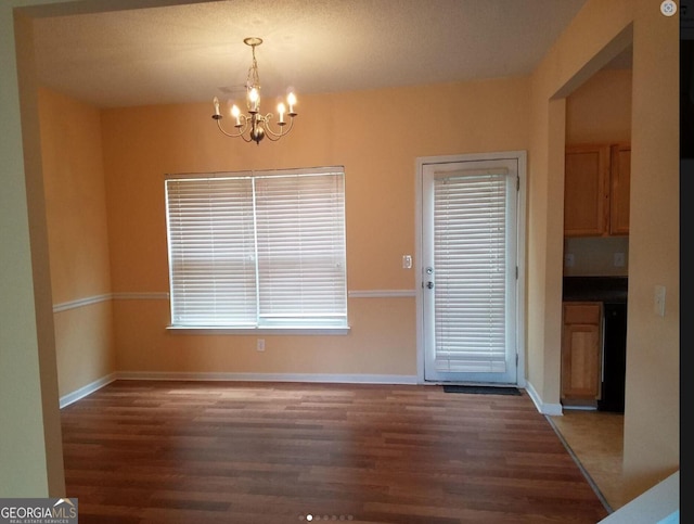 unfurnished dining area with dark hardwood / wood-style floors and an inviting chandelier