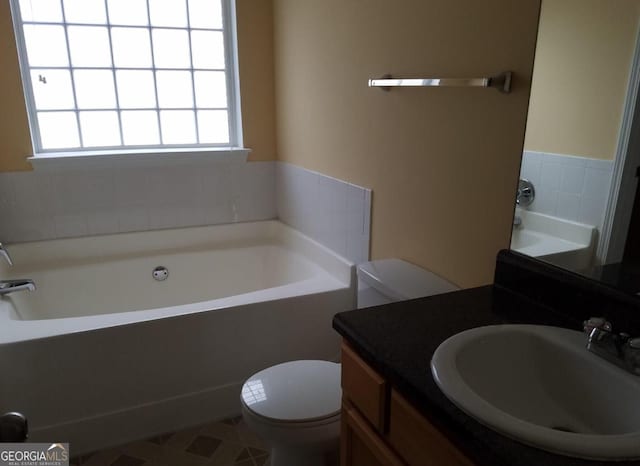 bathroom with vanity, a tub, and toilet