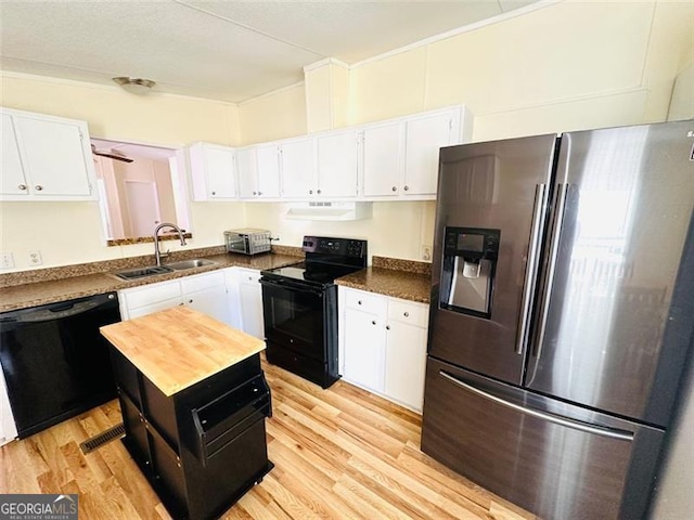 kitchen with light wood-style flooring, under cabinet range hood, a sink, white cabinets, and black appliances