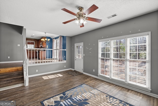 foyer featuring ceiling fan with notable chandelier, dark wood-type flooring, and a textured ceiling