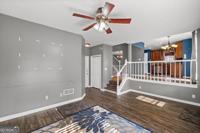 spare room featuring dark hardwood / wood-style floors, ceiling fan with notable chandelier, and a textured ceiling