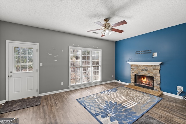 living room featuring dark hardwood / wood-style flooring, a textured ceiling, a fireplace, and a healthy amount of sunlight