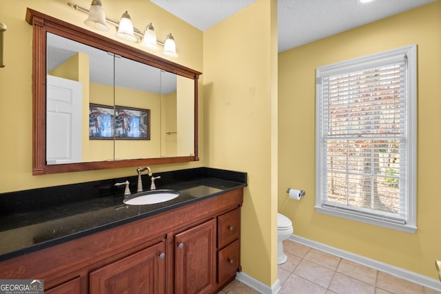 bathroom with vanity, a wealth of natural light, tile patterned floors, and toilet