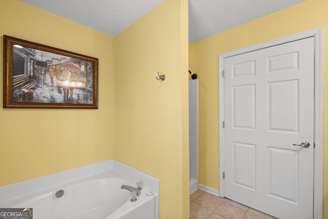 bathroom with tile patterned flooring, a washtub, and a textured ceiling