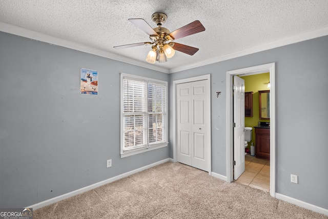 unfurnished bedroom with crown molding, light colored carpet, a textured ceiling, and a closet