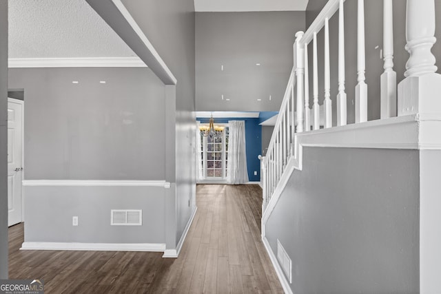 entryway with hardwood / wood-style floors, a notable chandelier, ornamental molding, and a textured ceiling