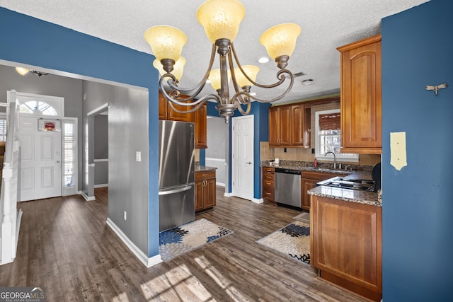 kitchen featuring sink, appliances with stainless steel finishes, an inviting chandelier, dark hardwood / wood-style floors, and decorative light fixtures