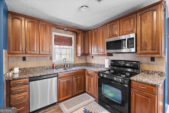 kitchen featuring stainless steel appliances, sink, decorative backsplash, and dark stone counters