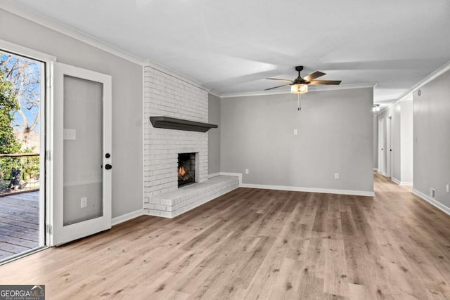 unfurnished living room featuring a healthy amount of sunlight, ornamental molding, light hardwood / wood-style floors, and a brick fireplace