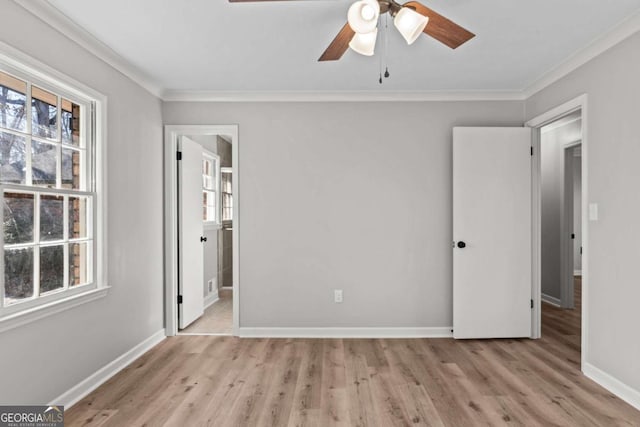 unfurnished bedroom featuring multiple windows, crown molding, and light wood-type flooring