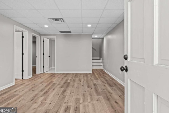 basement with a paneled ceiling and light hardwood / wood-style floors