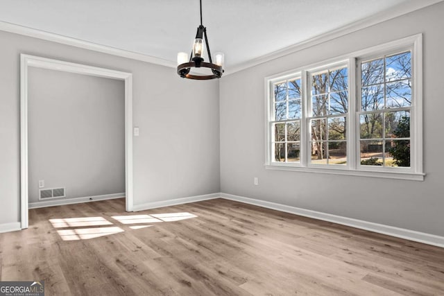 unfurnished dining area with an inviting chandelier, ornamental molding, and light hardwood / wood-style floors