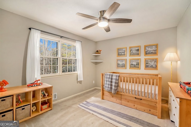 carpeted bedroom featuring a crib and ceiling fan