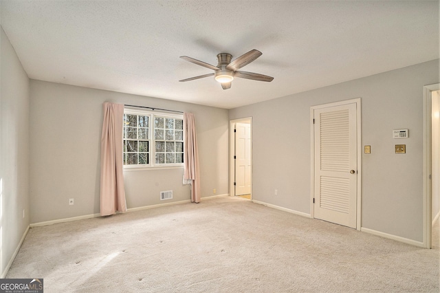 spare room featuring light carpet, a textured ceiling, and ceiling fan