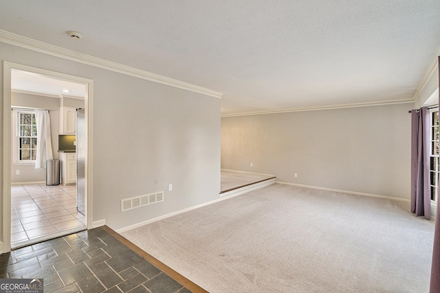 carpeted empty room featuring ornamental molding and a textured ceiling