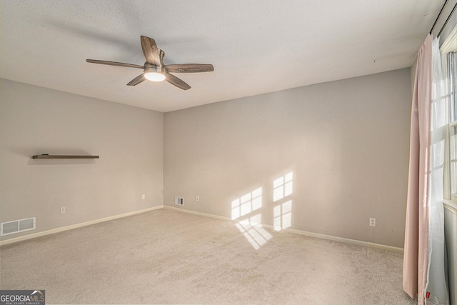 spare room with ceiling fan, light colored carpet, and a textured ceiling