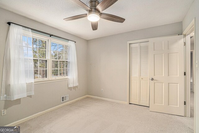 unfurnished living room with a stone fireplace, carpet floors, and a textured ceiling