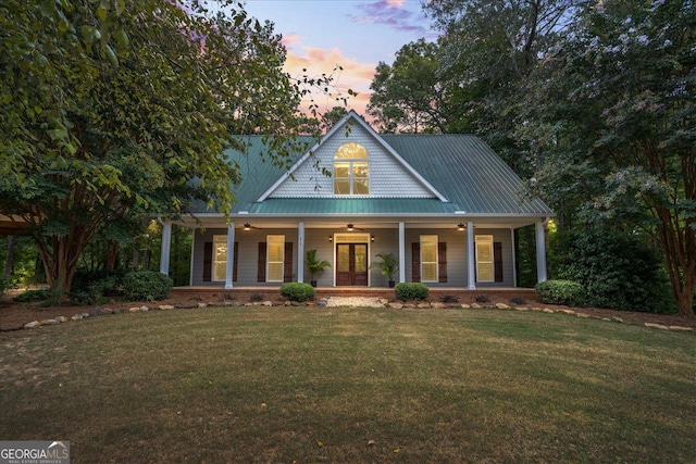 view of front of property with french doors, covered porch, and a lawn