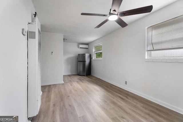 interior space with ceiling fan, an AC wall unit, and light wood-type flooring