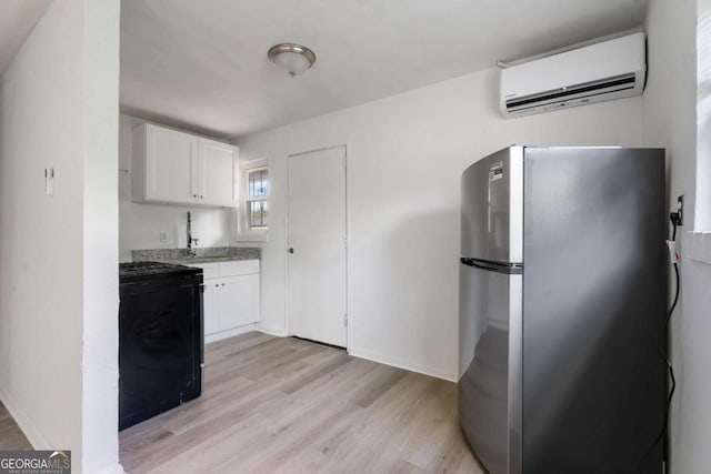 kitchen with stainless steel refrigerator, white cabinetry, range, and an AC wall unit