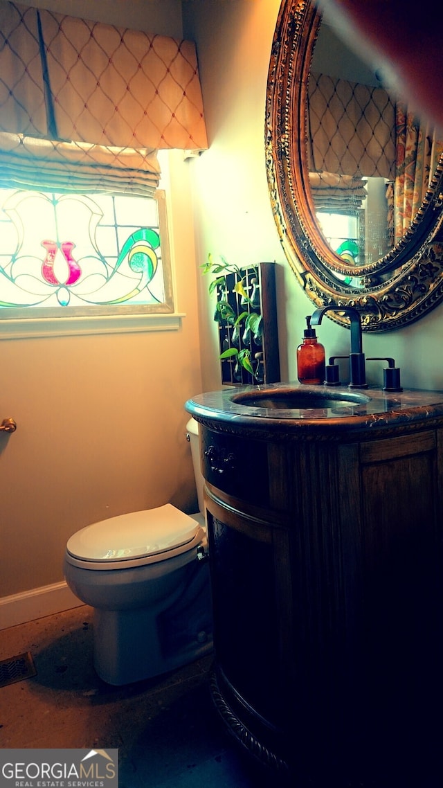 bathroom featuring baseboards, vanity, and toilet