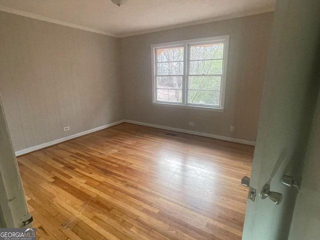 empty room with ornamental molding and light wood-type flooring