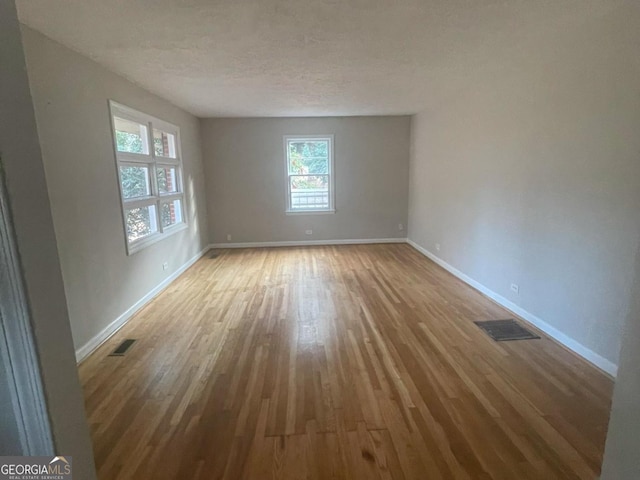 spare room featuring light hardwood / wood-style flooring and a textured ceiling