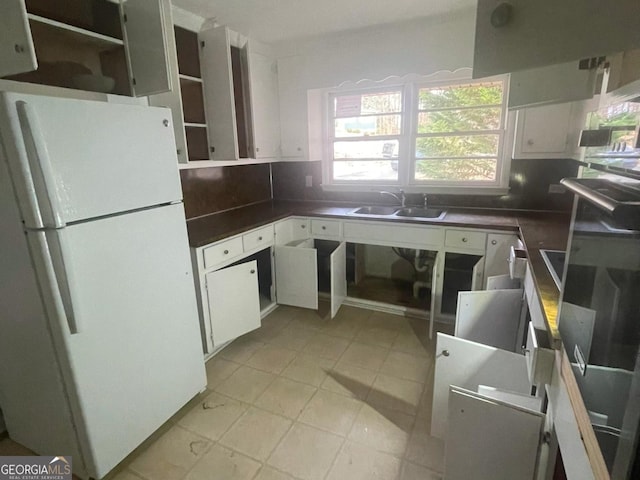 kitchen featuring sink, backsplash, white cabinets, and white fridge