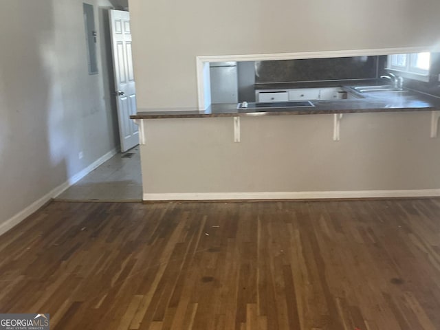 kitchen with sink, dark wood-type flooring, a kitchen breakfast bar, and kitchen peninsula