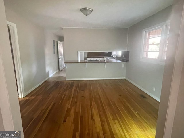 kitchen featuring dark hardwood / wood-style flooring, kitchen peninsula, a breakfast bar area, and white cabinets