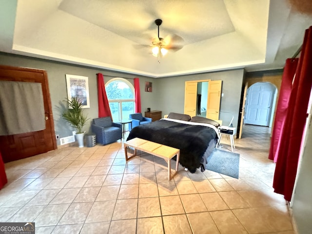 tiled bedroom with a tray ceiling and ceiling fan