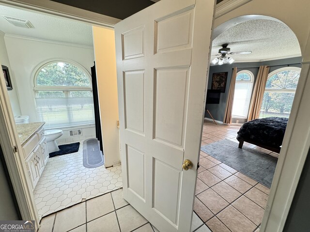 bathroom with ceiling fan, tile patterned flooring, a textured ceiling, and a wealth of natural light