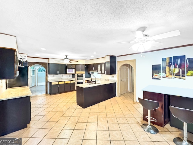 kitchen with sink, crown molding, light tile patterned floors, and ceiling fan