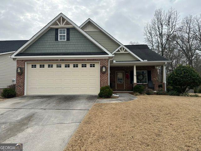 craftsman-style home featuring a garage, covered porch, and a front lawn